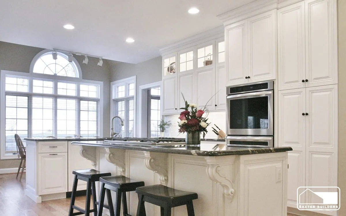 White custom kitchen remodel by Baxter Builders with an arched window, island seating and wall ovens
